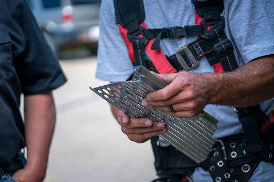 Perforated aluminum gutter protection profile being handled during manufacturer training