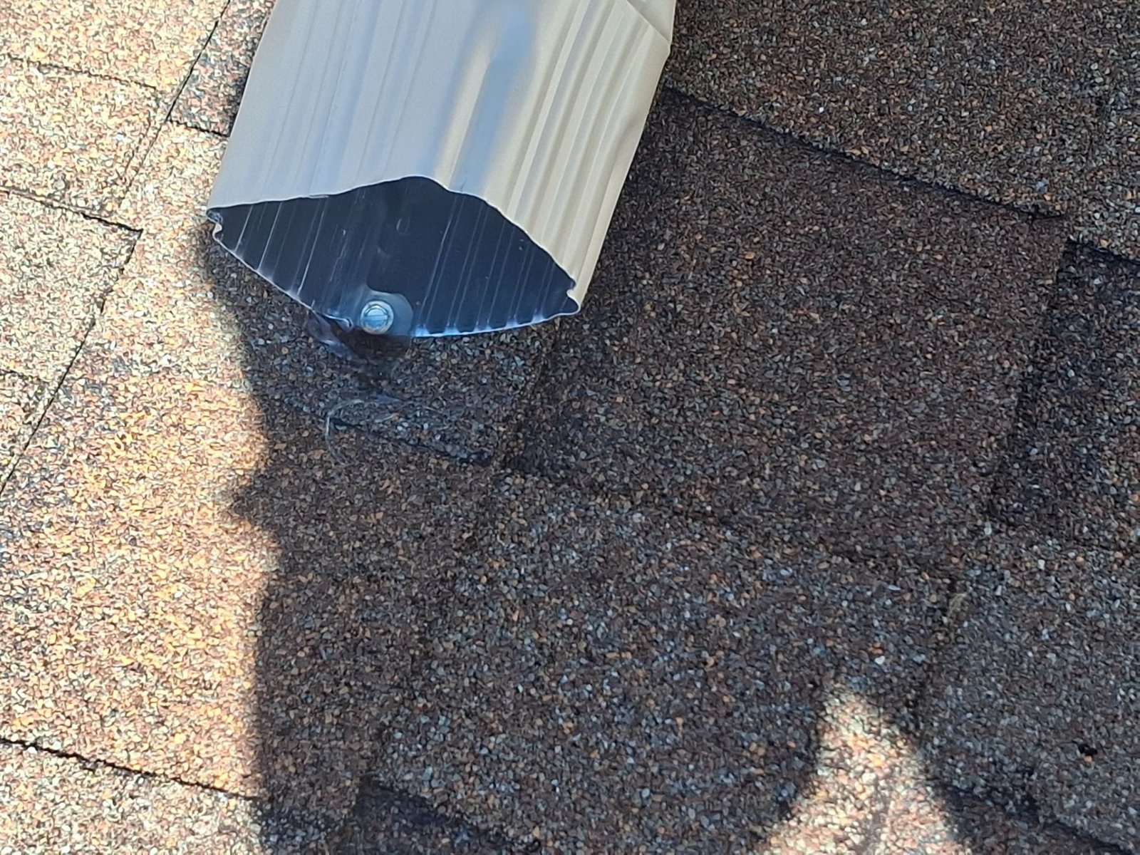 Field example showing a fastener through a downspout water path on a gutter system not installed by McCloud Gutter.