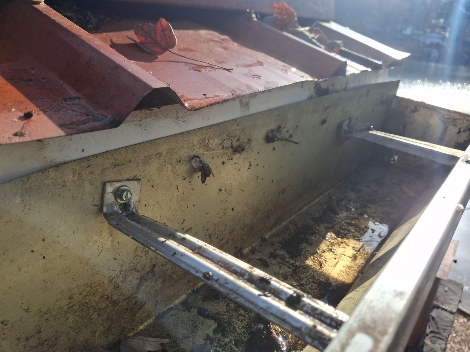 Field example showing hangers and screws placed at different heights and angles through the back of a gutter not installed by McCloud Gutter.