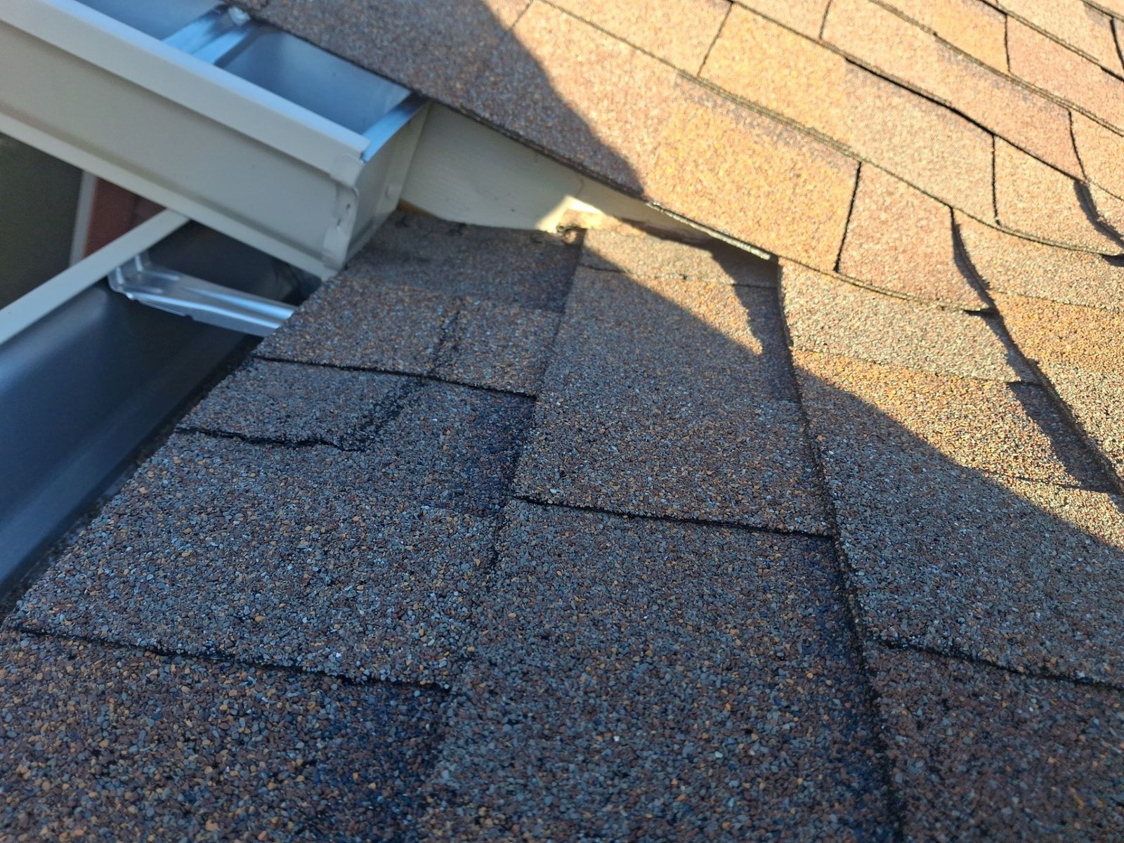 Field example showing a gutter end tight to shingles where roof water can be redirected on a system not installed by McCloud Gutter.
