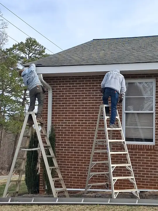Devin and Jacob installing white seamless gutter