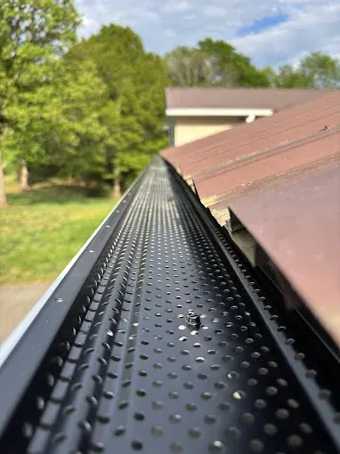 E-Z Smooth Flow perforated aluminum gutter guard installed by McCloud Gutter on a white 6-inch gutter in Conover North Carolina
